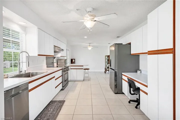 Kitchen with white cabinetry, stainless steel appliances, light tile patterned floors, and ceiling fan
