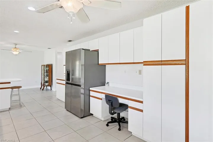 Tiled office featuring a textured ceiling, built in desk, and ceiling fan