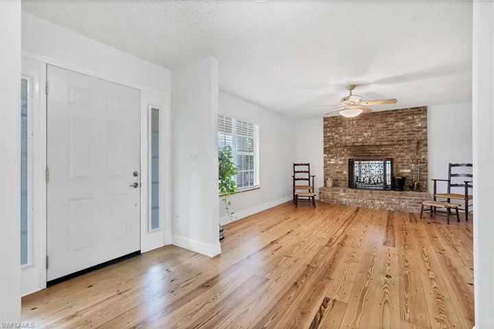 Foyer entrance featuring light hardwood / wood-style floors, a fireplace, ceiling fan, and a textured ceiling