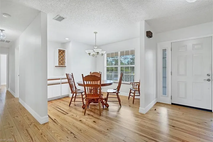Dining space featuring a textured ceiling, light hardwood / wood-style flooring, and a notable chandelier