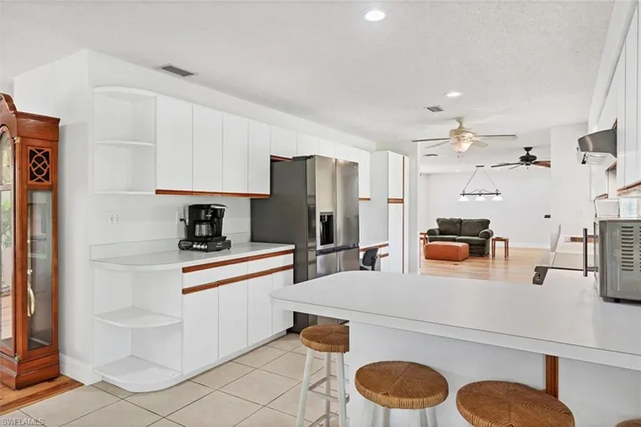Kitchen with white cabinetry, kitchen peninsula, a kitchen breakfast bar, and ceiling fan