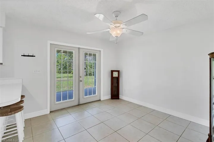 Tiled spare room with a textured ceiling, ceiling fan, and french doors