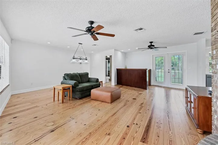 Living area featuring light hardwood / wood-style floors, a textured ceiling, french doors, and ceiling fan