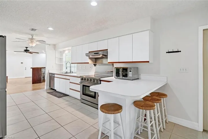 Kitchen with appliances with stainless steel finishes, a textured ceiling, ceiling fan, and white cabinets