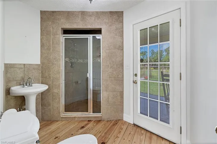 Bathroom featuring an enclosed shower, tile walls, wood-type flooring, and toilet