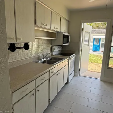 Kitchen featuring electric stove, stainless steel microwave, light countertops, and decorative backsplash