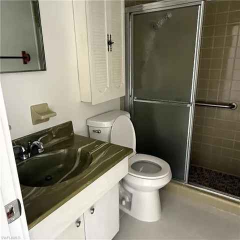 Full bath with vanity, light tile patterned floors, and a stall shower