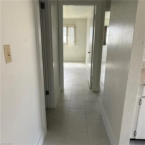 Hallway featuring a textured wall and light tile patterned flooring