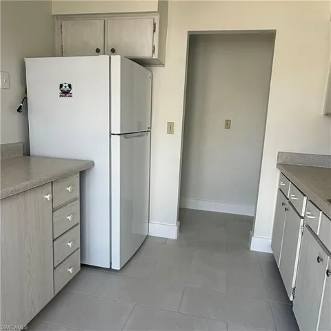 Kitchen with freestanding refrigerator, light countertops, and dark tile patterned floors