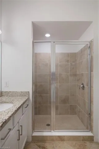 Bathroom with vanity, tile patterned floors, and a shower with door