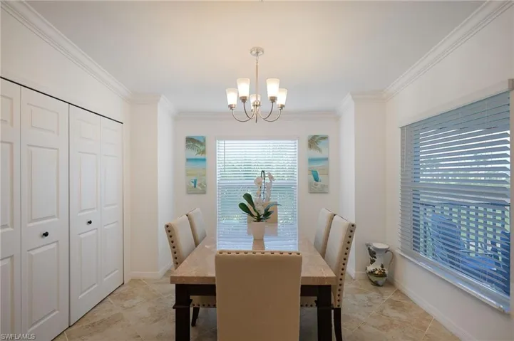 Dining area with crown molding, light tile patterned flooring, and a notable chandelier