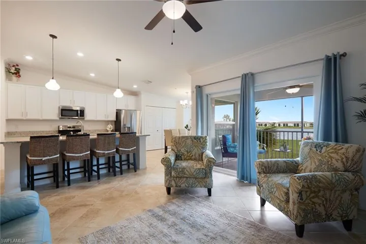 Tiled living room featuring lofted ceiling, ornamental molding, and ceiling fan