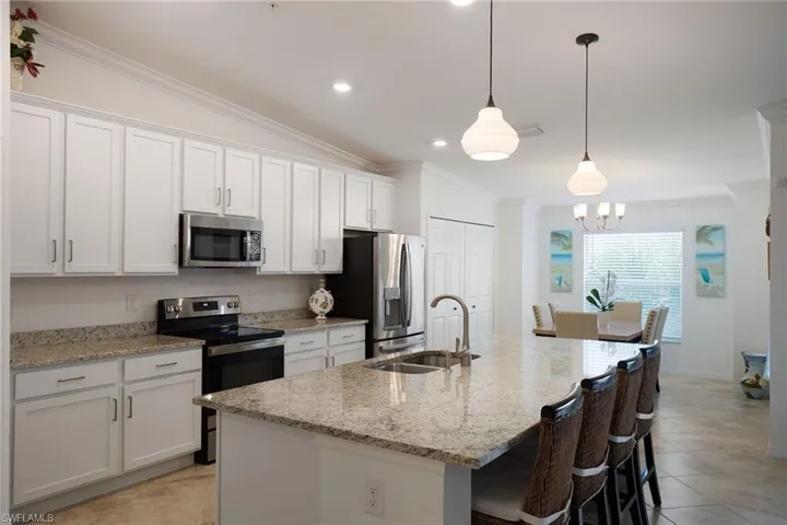 Kitchen featuring a kitchen island with sink, pendant lighting, white cabinets, and stainless steel appliances