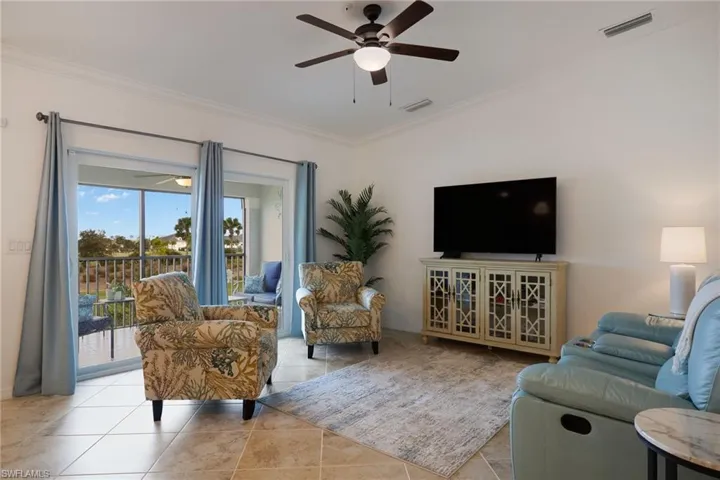 Living room with crown molding, light tile patterned flooring, and ceiling fan