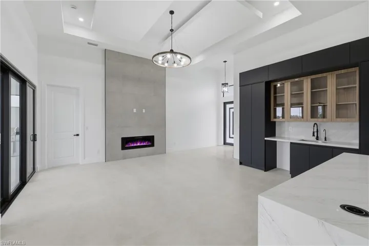 Kitchen featuring dark cabinets, a high ceiling, modern cabinets, glass insert cabinets, and decorative light fixtures