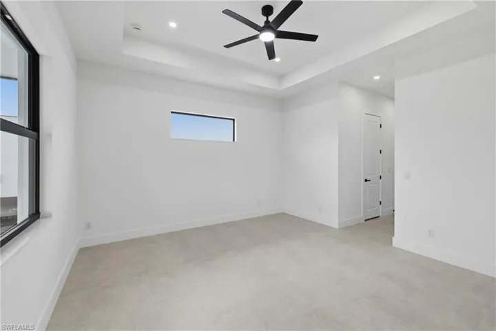 Unfurnished room with a raised ceiling, ceiling fan, and recessed lighting