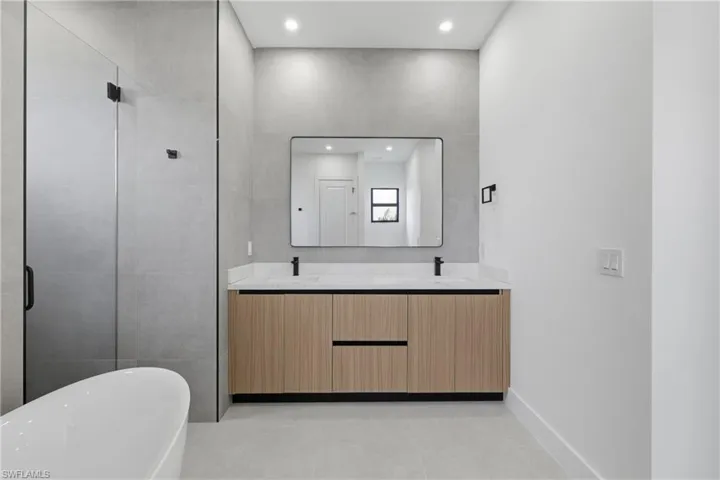 Full bathroom featuring double vanity, a freestanding tub, recessed lighting, a shower stall, and light tile patterned flooring