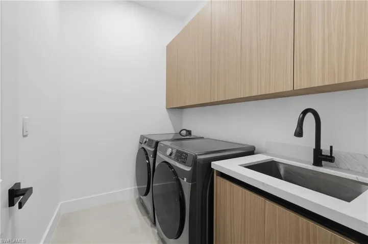 Washroom featuring independent washer and dryer, cabinet space, and light tile patterned flooring
