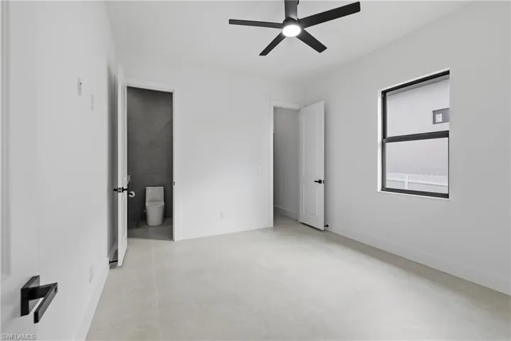 Unfurnished bedroom featuring ceiling fan and connected bathroom