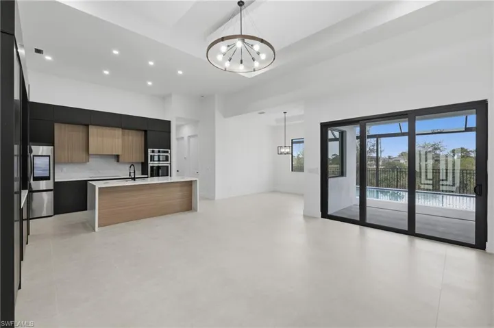 Kitchen with modern cabinets, a chandelier, decorative light fixtures, open floor plan, and a towering ceiling