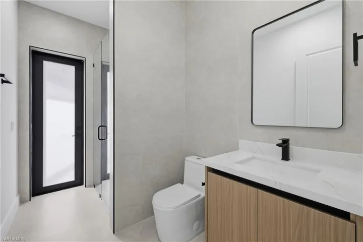 Full bath featuring vanity, a shower stall, and tile walls