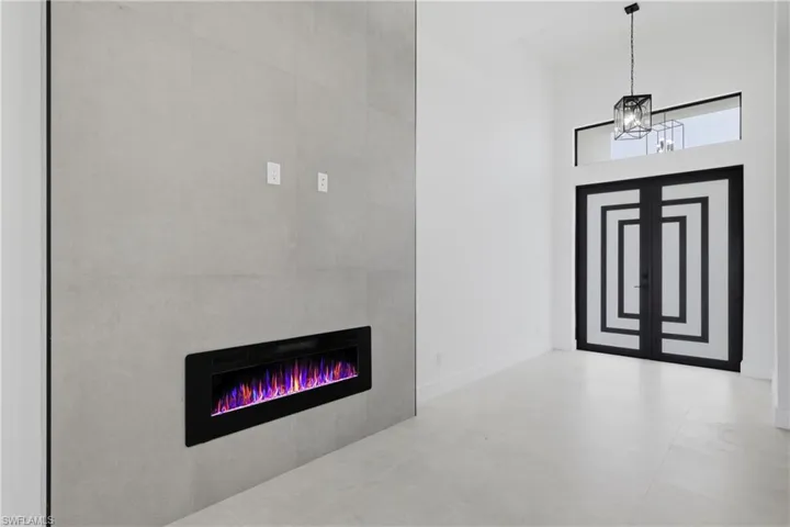 Entryway featuring a glass covered fireplace, a towering ceiling, and a chandelier