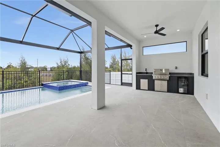 View of pool with area for grilling, a pool with connected hot tub, a sunroom, and glass enclosure