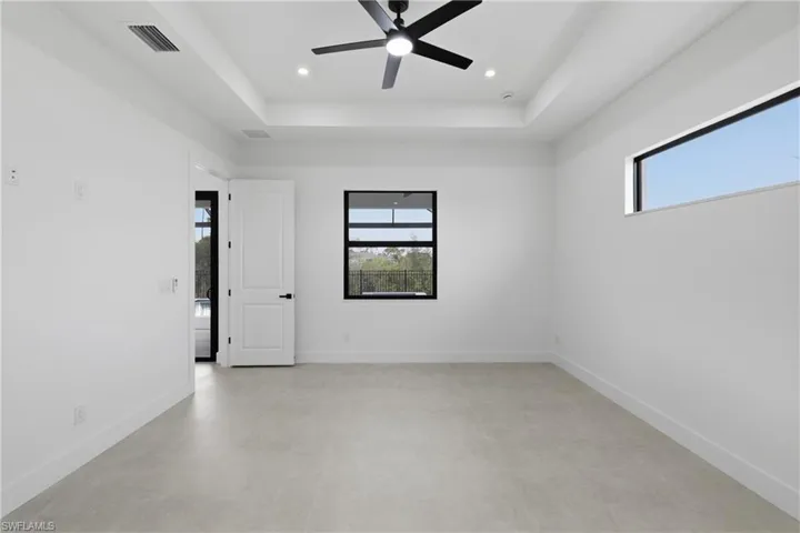 Empty room featuring a raised ceiling, a ceiling fan, and recessed lighting
