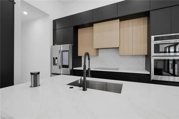 Kitchen featuring dark cabinets, modern cabinets, light brown cabinets, stainless steel appliances, and recessed lighting