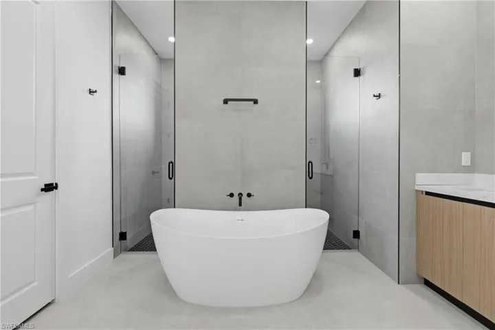 Full bath featuring a soaking tub, a shower stall, tile walls, and vanity