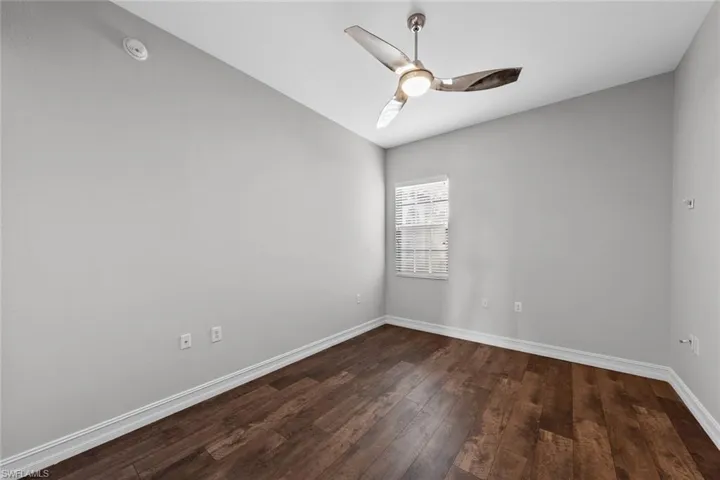 Spare room featuring dark wood-type flooring and a ceiling fan