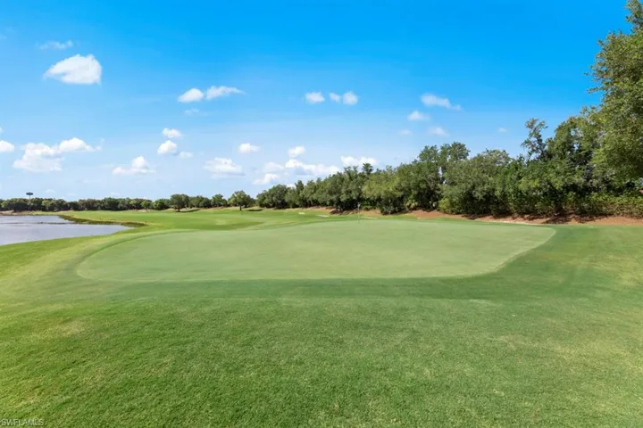 View of community with golf course view, a water view, and view of scattered trees
