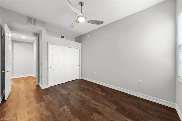 Unfurnished bedroom with dark wood-style flooring, a ceiling fan, and a closet
