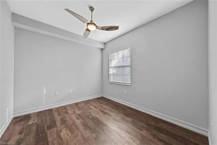 Empty room featuring dark wood-type flooring and a ceiling fan