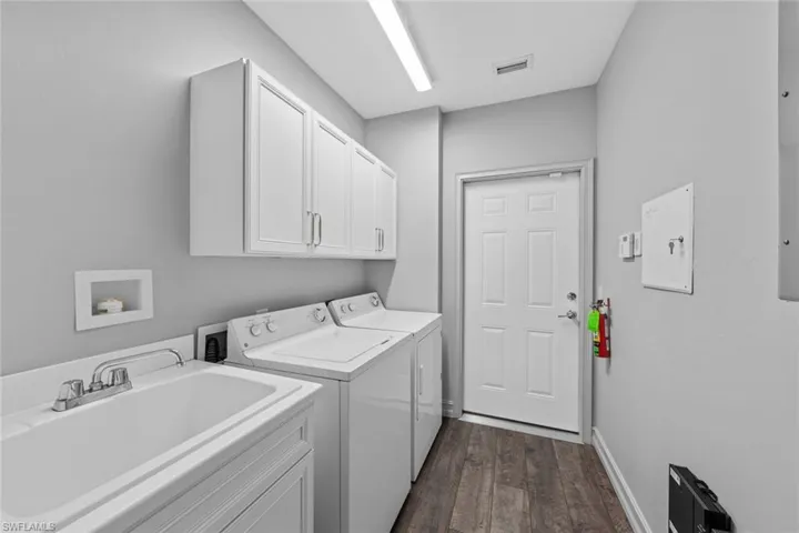 Laundry area featuring cabinet space, dark wood-style flooring, and washing machine and clothes dryer