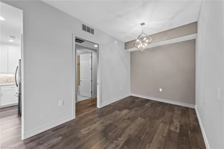 Unfurnished dining area with dark wood-style flooring and a chandelier