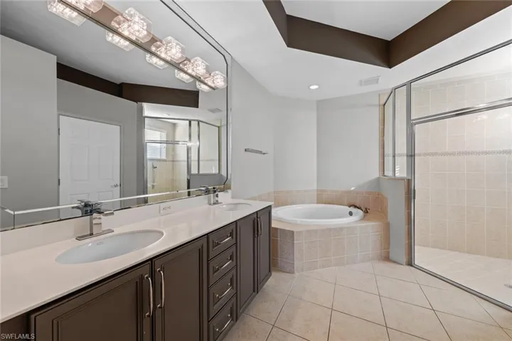 Bathroom with tile patterned floors, a shower stall, a garden tub, and double vanity