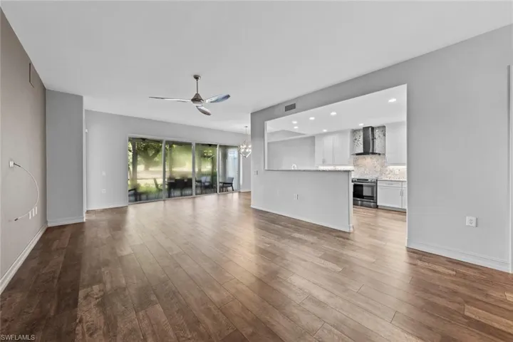 Unfurnished living room with ceiling fan, a chandelier, wood finished floors, and recessed lighting