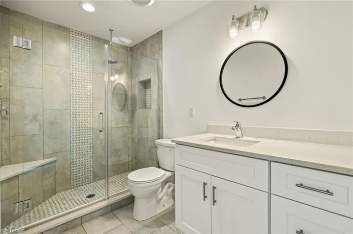 Full bathroom featuring toilet, tile patterned floors, a stall shower, vanity, and recessed lighting