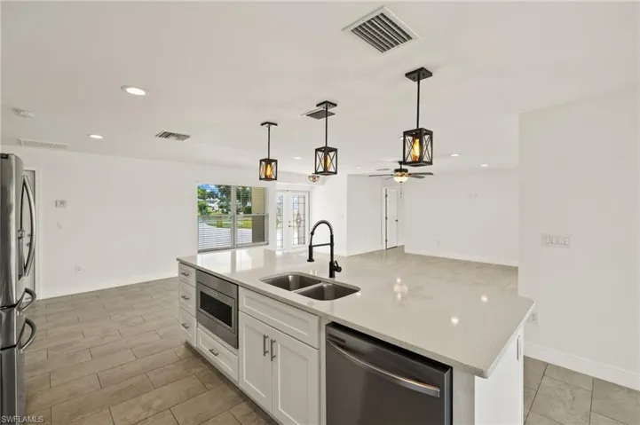 Kitchen with stainless steel appliances, a sink, white cabinets, recessed lighting, and decorative light fixtures