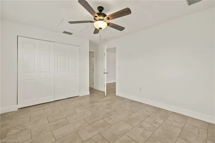 Unfurnished bedroom featuring a closet, baseboards, a ceiling fan, and light tile patterned flooring