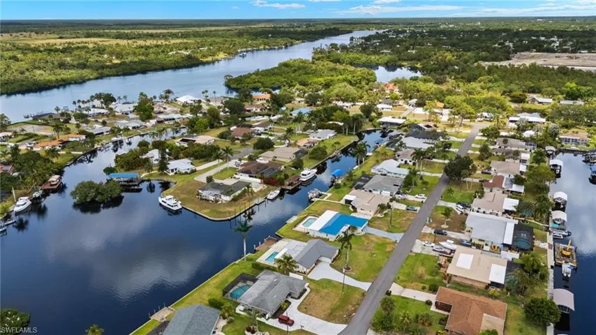 Aerial overview of property's location featuring a large body of water, nearby suburban area, and a forest
