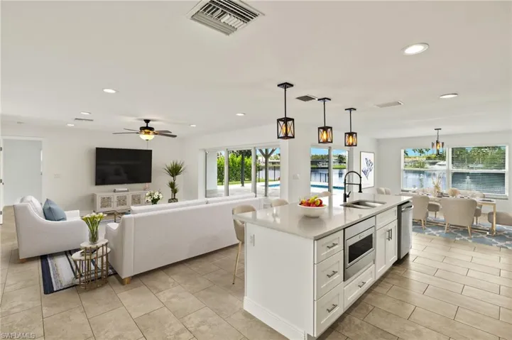 Kitchen featuring a sink, stainless steel appliances, recessed lighting, open floor plan, and white cabinetry
