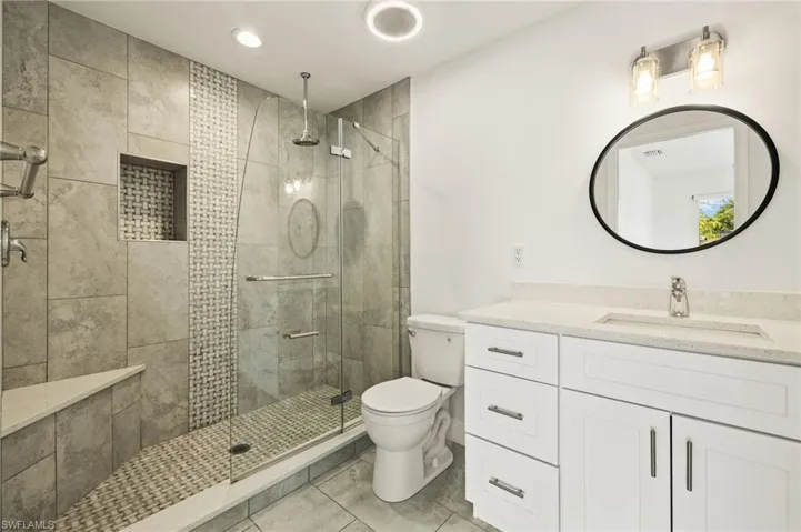 Full bath featuring toilet, tile patterned flooring, a tile shower, vanity, and recessed lighting