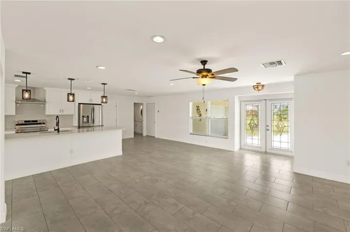 Unfurnished living room with ceiling fan, recessed lighting, a sink, french doors, and baseboards