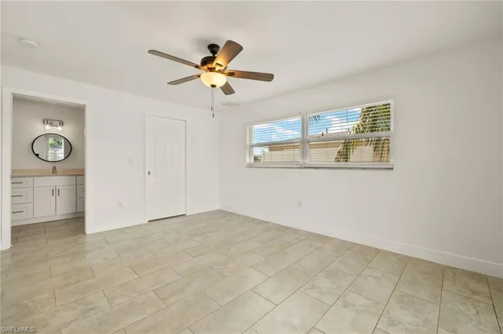 Unfurnished bedroom with baseboards, ceiling fan, and ensuite bath