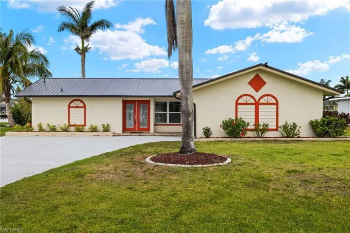 Single story home with french doors, stucco siding, a front lawn, and metal roof