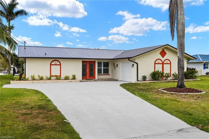 Ranch-style home featuring stucco siding, an attached garage, metal roof, concrete driveway, and a front yard