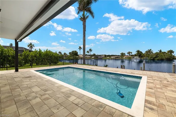 Swimming pool featuring a water view, a patio, and fence