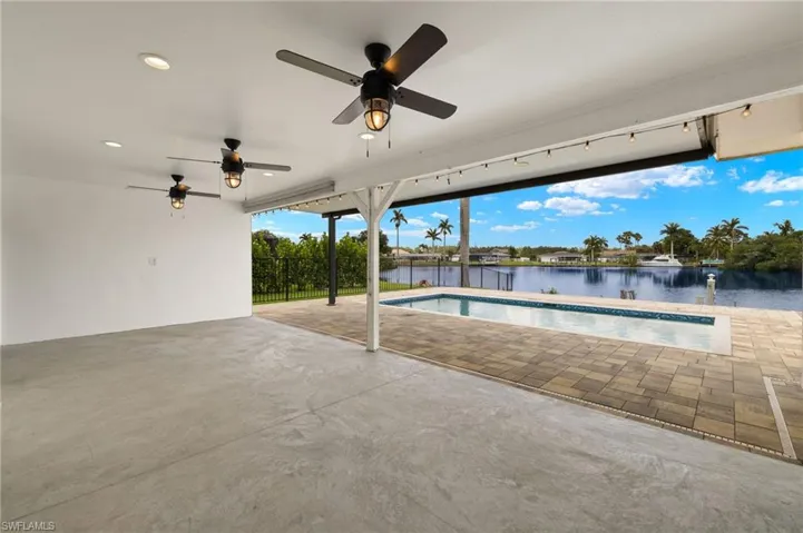 Outdoor pool featuring a patio, a water view, ceiling fan, and fence